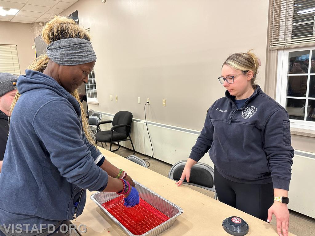 Firefighter Judith Le Gall practices taking off her &quot;blood soaked&quot; medical gloves as Lead Foreman Elly Hersam looks on - 01/29/24