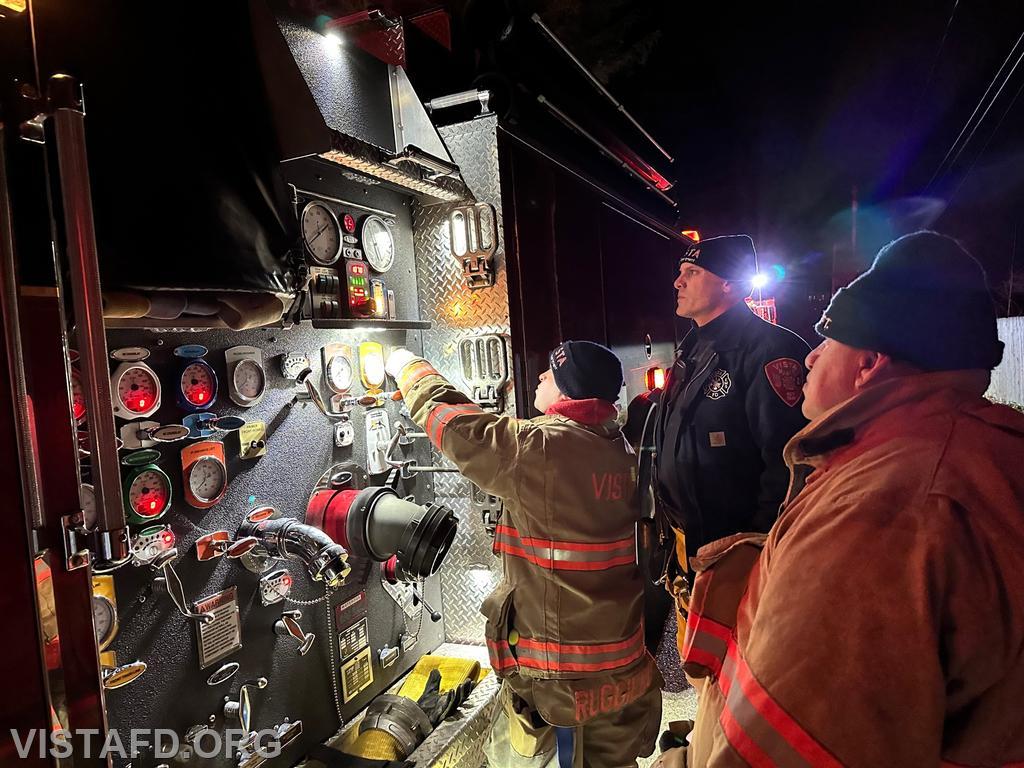 Foreman Ryan Ruggiero operating the Engine 141 pump panel during a hydrant service as Lt. Marc Baiocco and Firefighter Martin Rojas look on