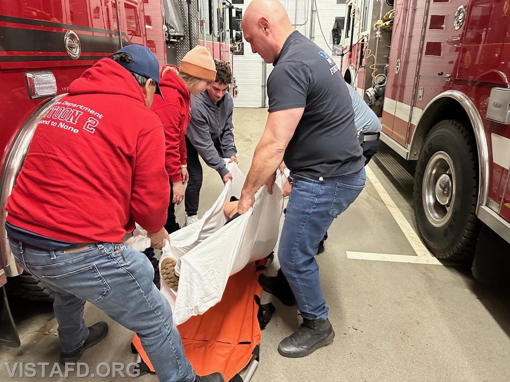 Vista Fire Department personnel going over how to move a patient from a bed sheet onto the reeves stretcher
