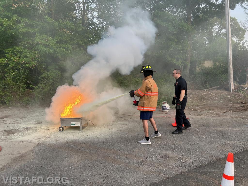 Members of the community learning how to use a fire extinguisher from Assistant Chief Brian Porco