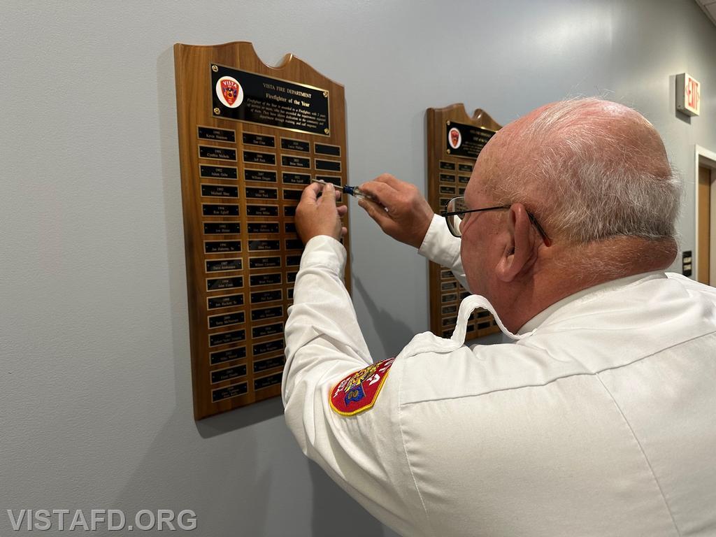 Firefighter Ron Egloff putting his name on the Vista Fire Department "Firefighter of the Year" plaque