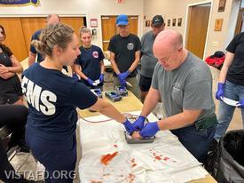 Firefighter Steven Woodstead going over how to apply a tourniquet as Lead Foreman Elly Hersam looks on