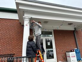 Probationary Firefighter Ty Graygor and Probationary Firefighter Guillaume Pestie putting lights up around the Vista Firehouse