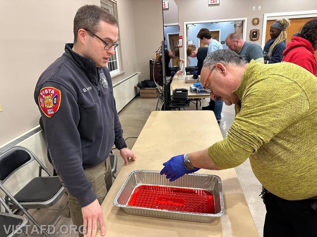Firefighter Mark Albert practices taking off his "blood soaked" medical gloves as Assistant Chief Brian Porco looks on