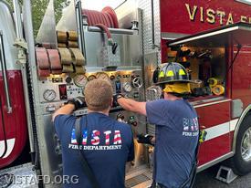Firefighter Phil Wanderman operating the Engine 142 pump panel as Lead Foreman Mike Peck looks on
