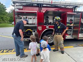 Ex-Chief Jim Hackett and Foreman Pietro Cipriano giving campers a tour of Engine 141 and its equipment