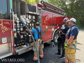 Lead Foreman Ryan Ruggiero operating the Engine 141 pump panel as Foreman Martin Rojas explains pump operations to Firefighter Judith Le Gall