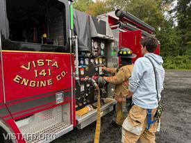 Foreman Pietro Cipriano reviewing operation of the Engine 141 pump panel with Firefighter/EMT Ashtin Rama during Driver Training